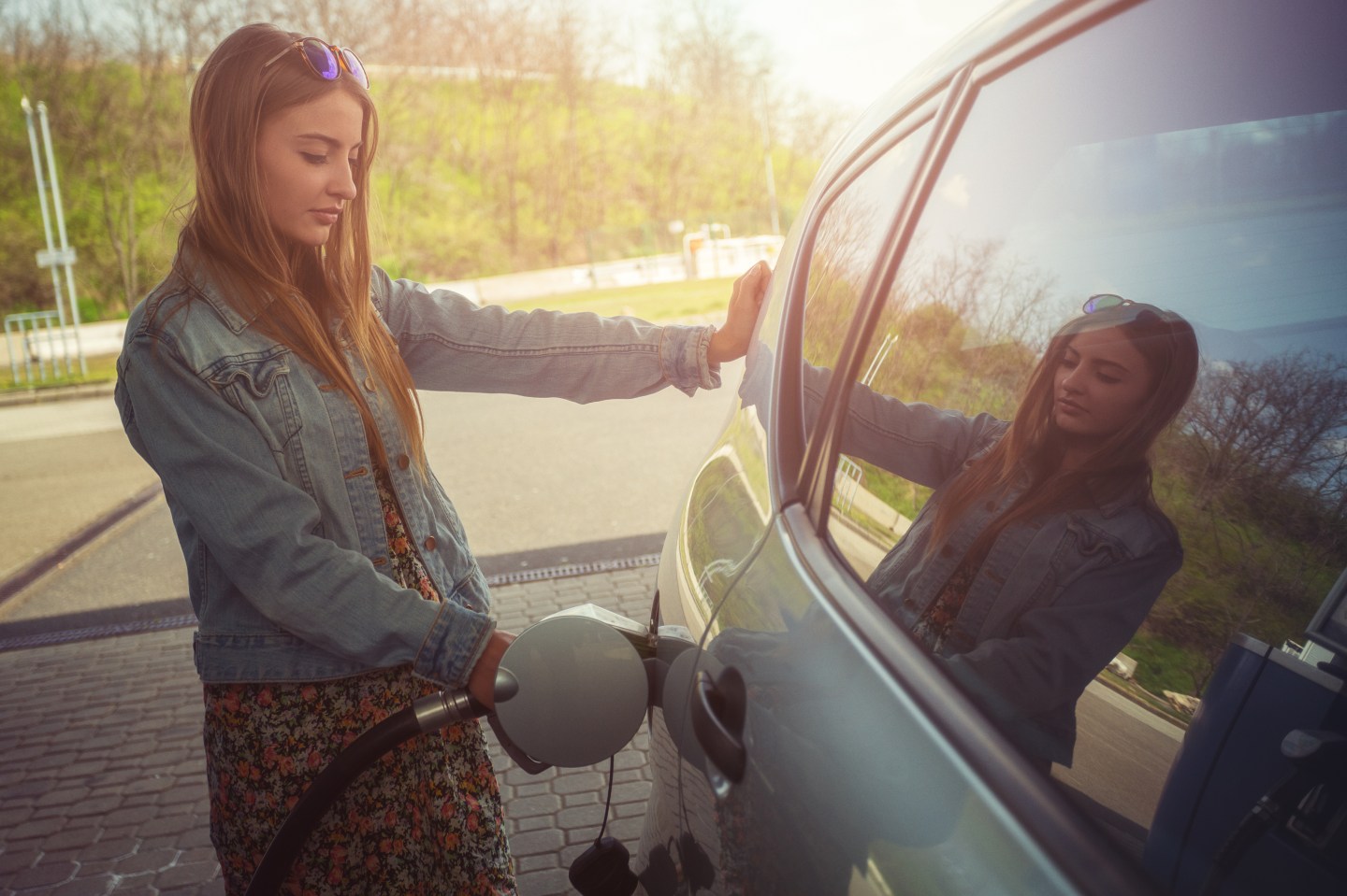Young woman refilling car with gas pump