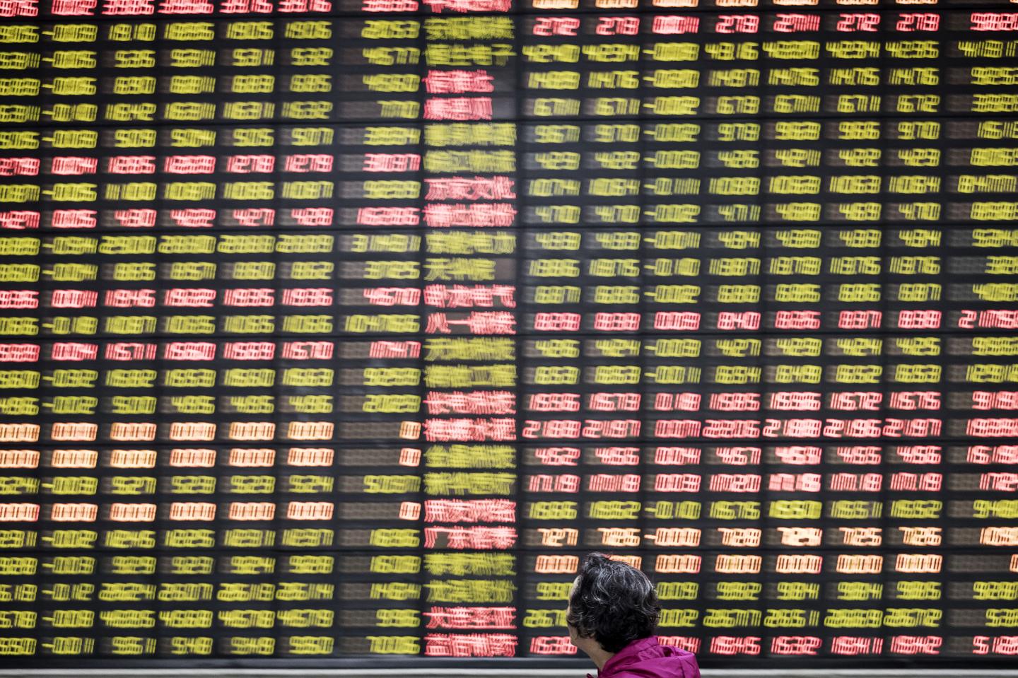 An investor looks up at an electronic stock board at a securities brokerage in Shanghai, China, on Friday, June 9, 2017.