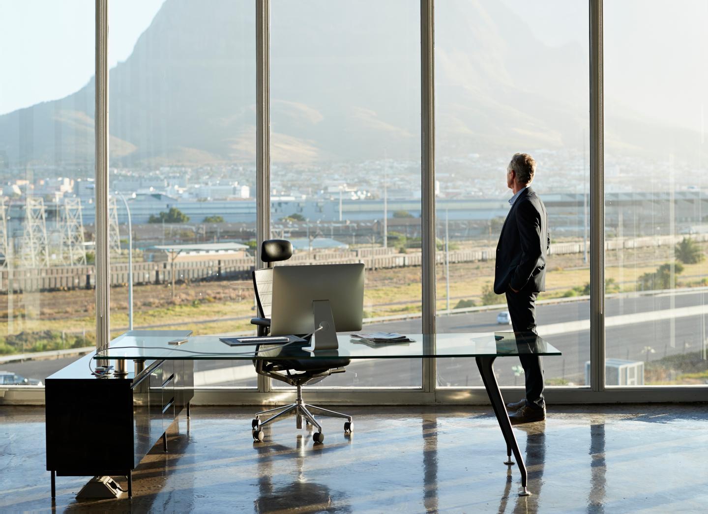 Portrait of male CEO in big corner office, looking out of window