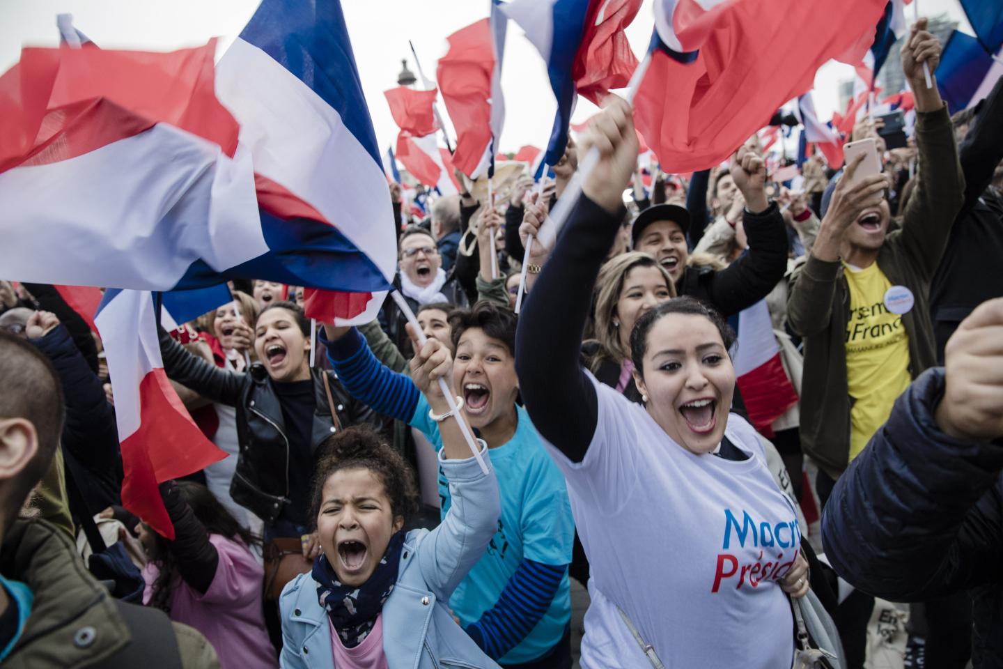 Supporters wave French national flags ahead of a speech by Emmanuel Macron, near the Louvre museum in Paris, on May 7, 2017.