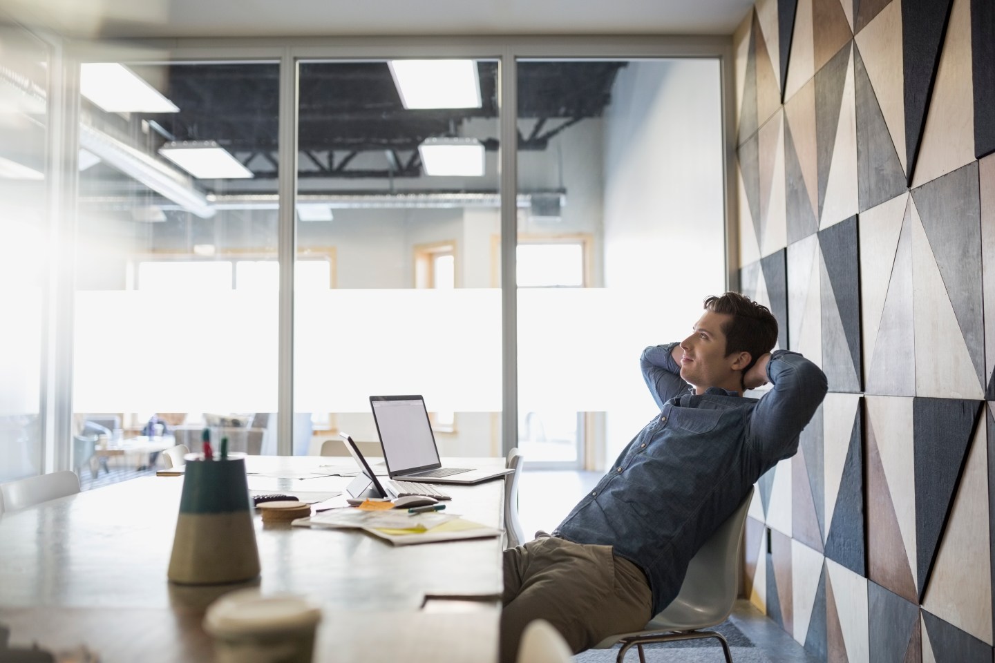Casual businessman relaxing hands behind head conference room