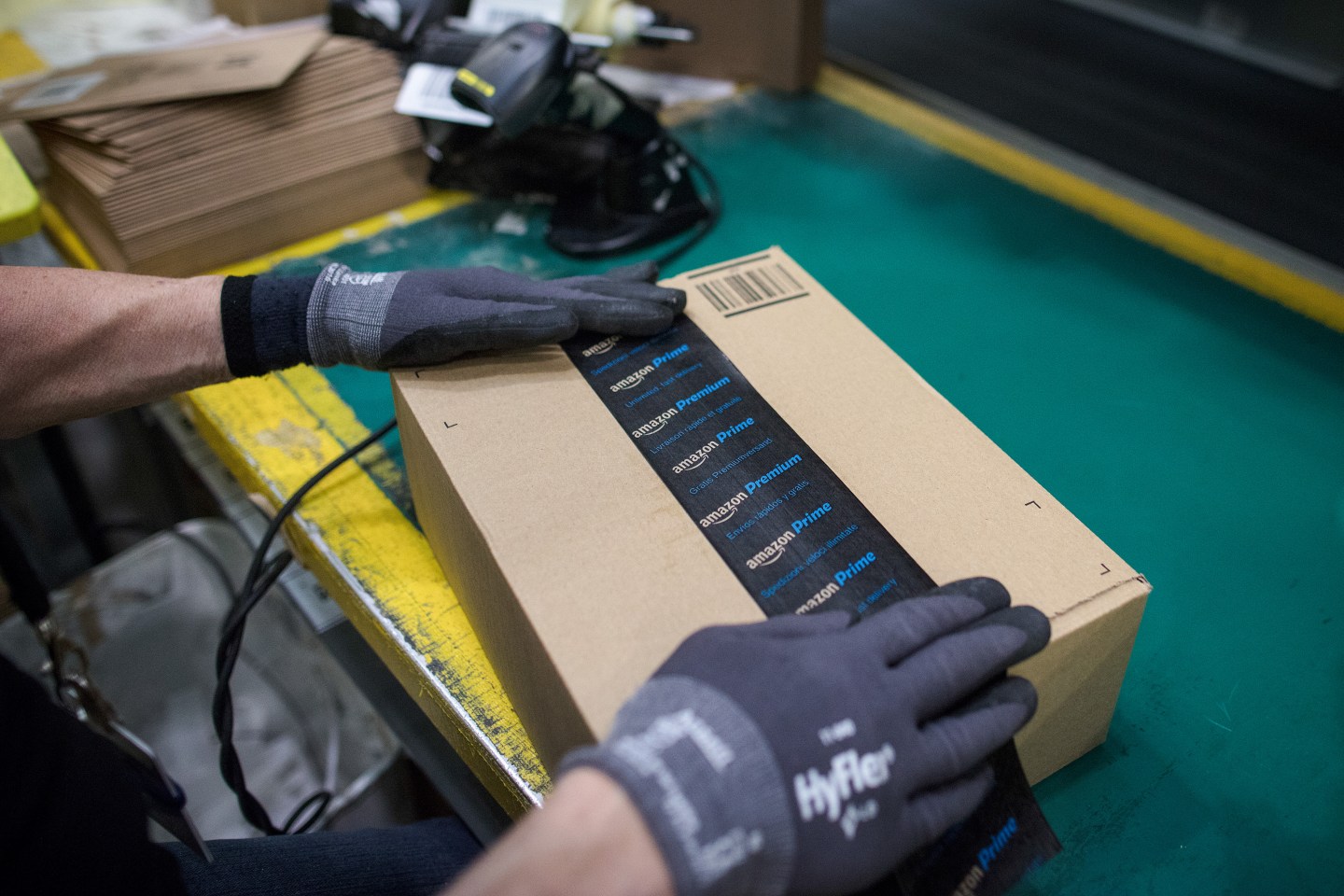 An employee seals a delivery box with tape with Amazon Prime and Amazon Premium branding at a fulfillment center in the UK.