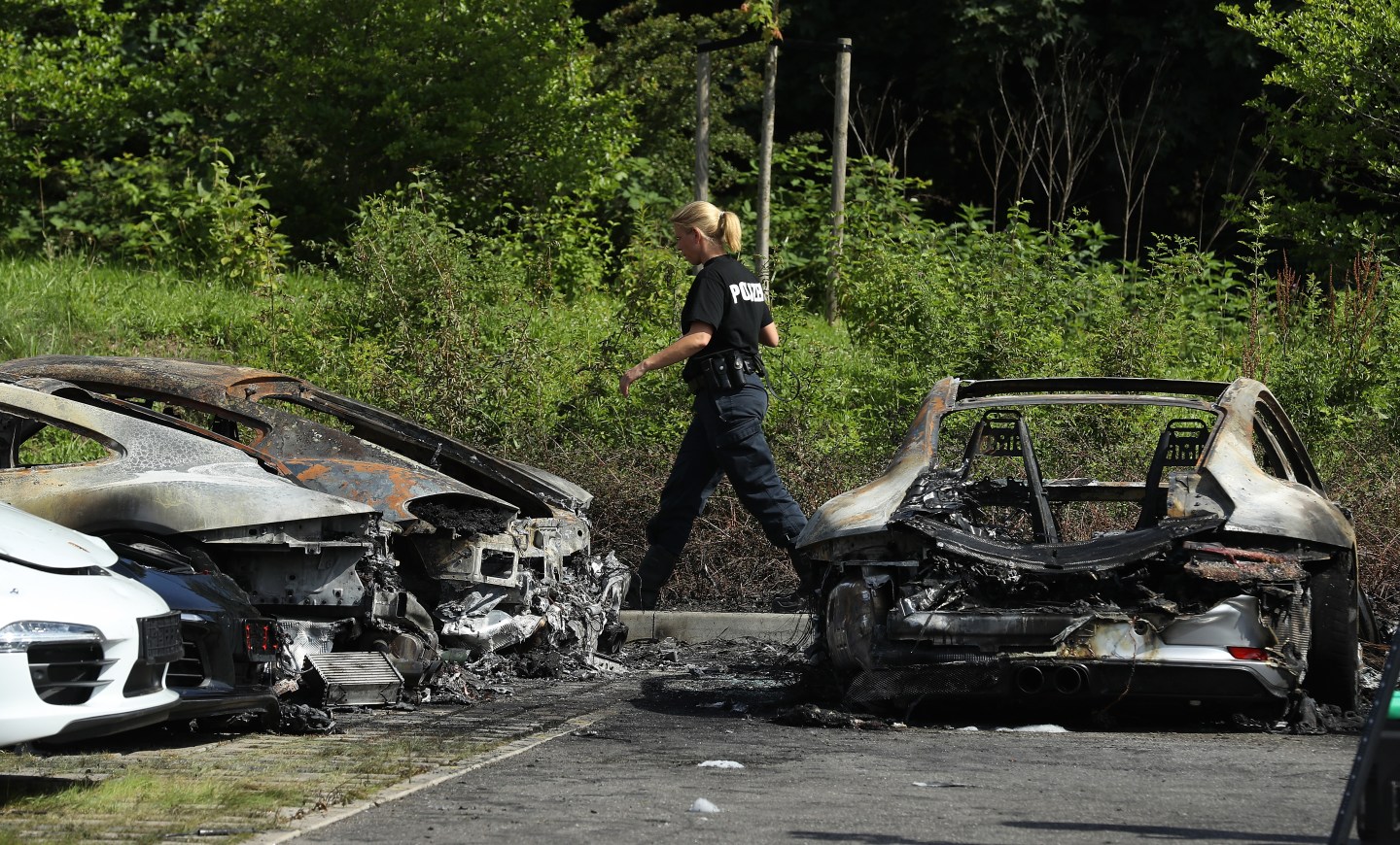 A police investigator walks past Porsche cars that were among 10 set alight by an arsonist at a Porsche dealership on July 6, 2017 in Hamburg, Germany.