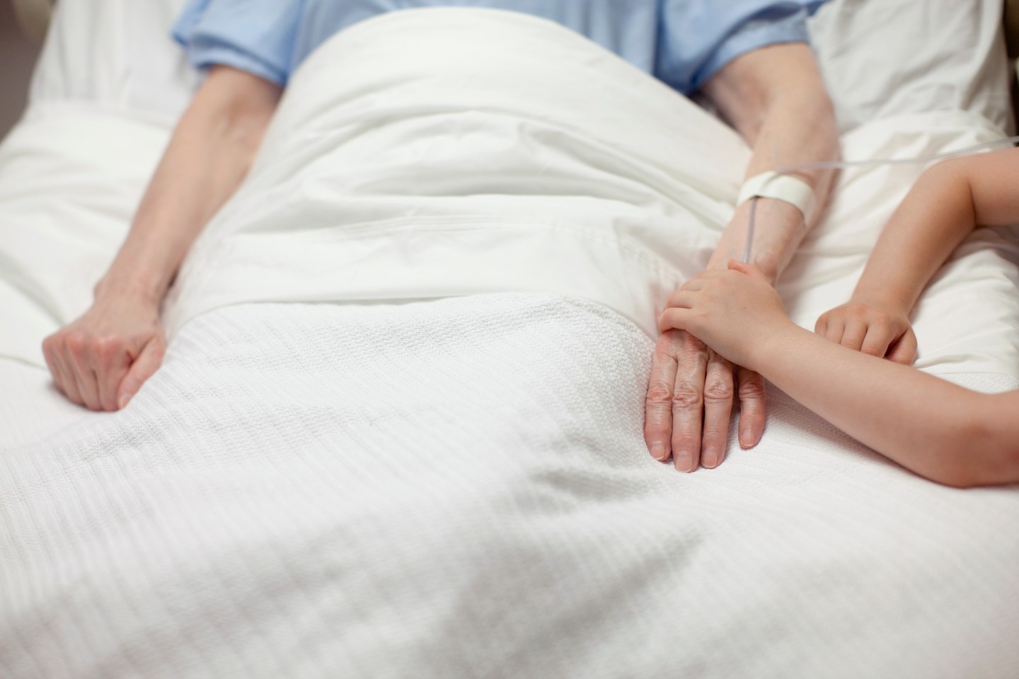 Young girl holding grandma's hand in hospital