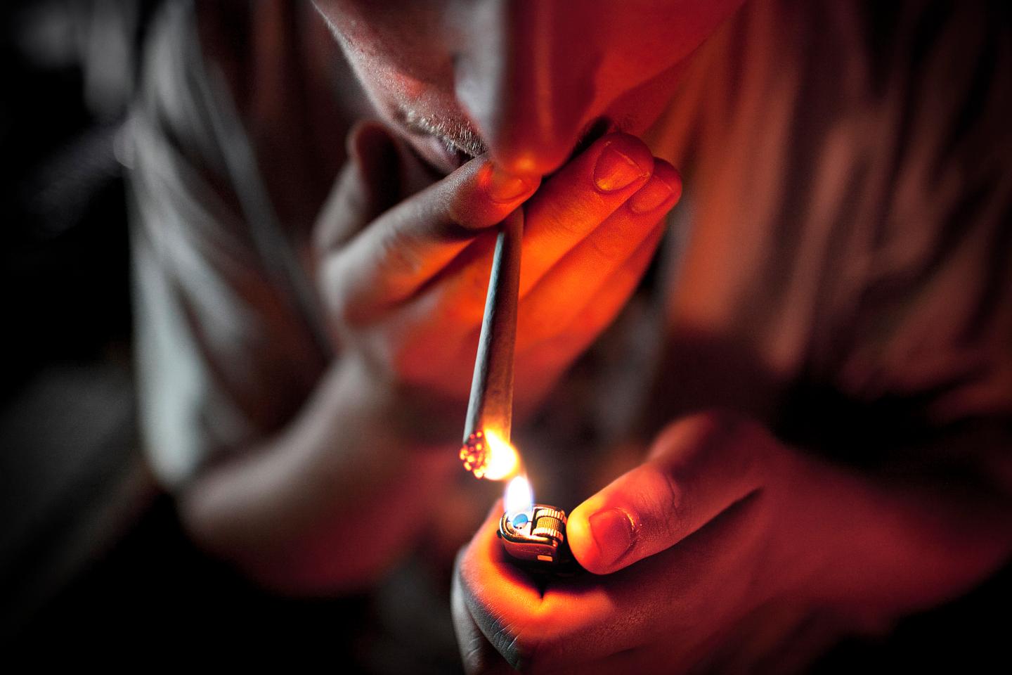 Young man lights up a joint.