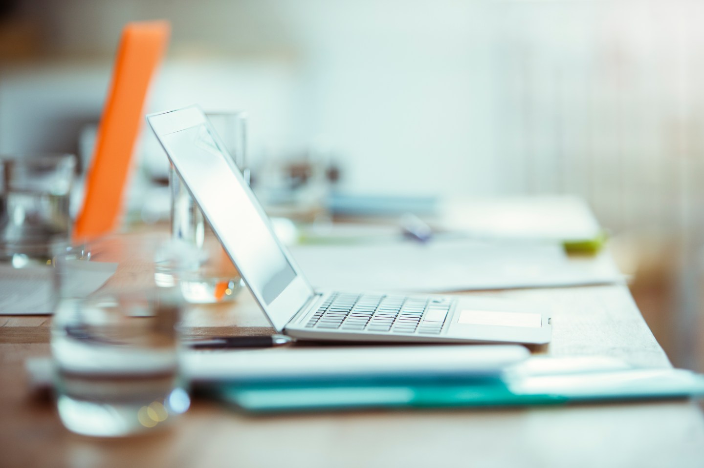 Office supplies, laptop and glass of water on desk in office