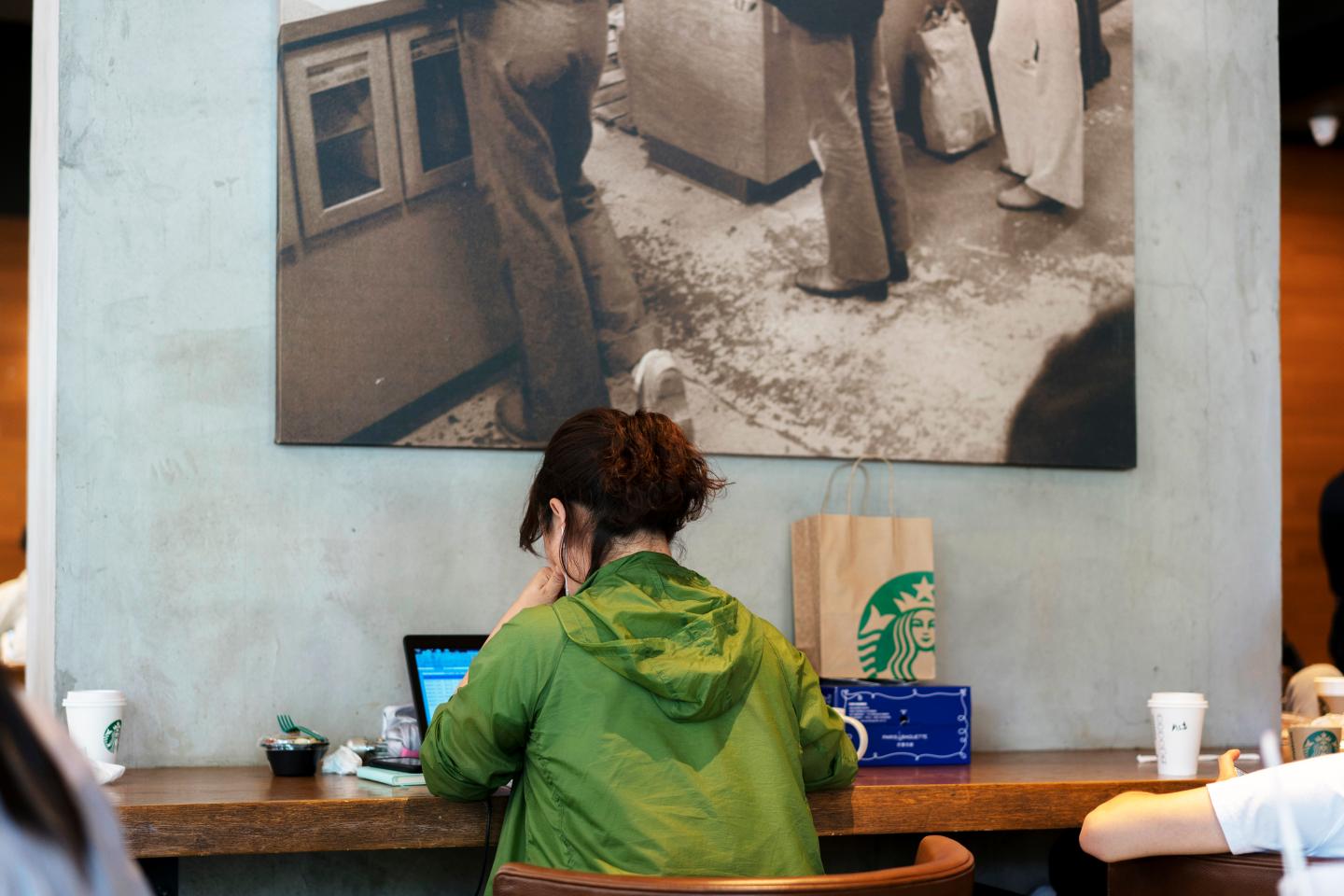 A girl is working on laptop in a Starbucks coffee shop. In