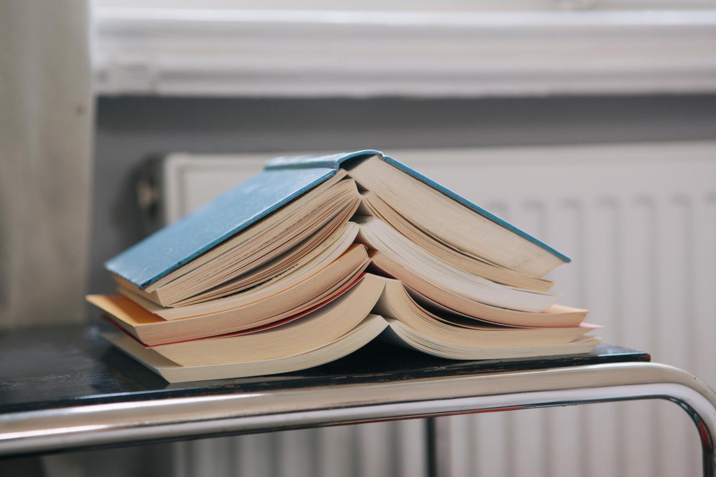 Close-up of stacked open books on table
