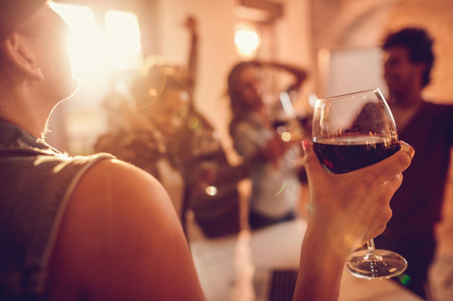 Close up of woman enjoying in wine at office party.
