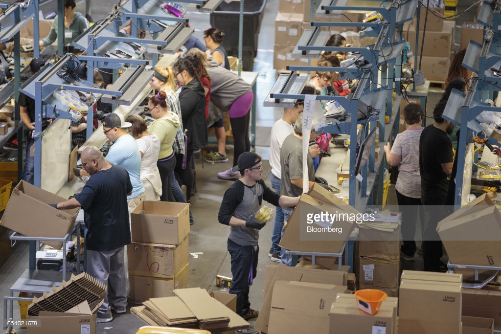 Workers place products into boxes for shipping at the OtterBox distribution center in Frederick, Colorado, U.S., on Tuesday, March 14, 2017. Otterbox, founded in 1998, produces water resistant, shock resistant, and drop resistant cases for mobile devices. Photographer: Matthew Staver/Bloomberg