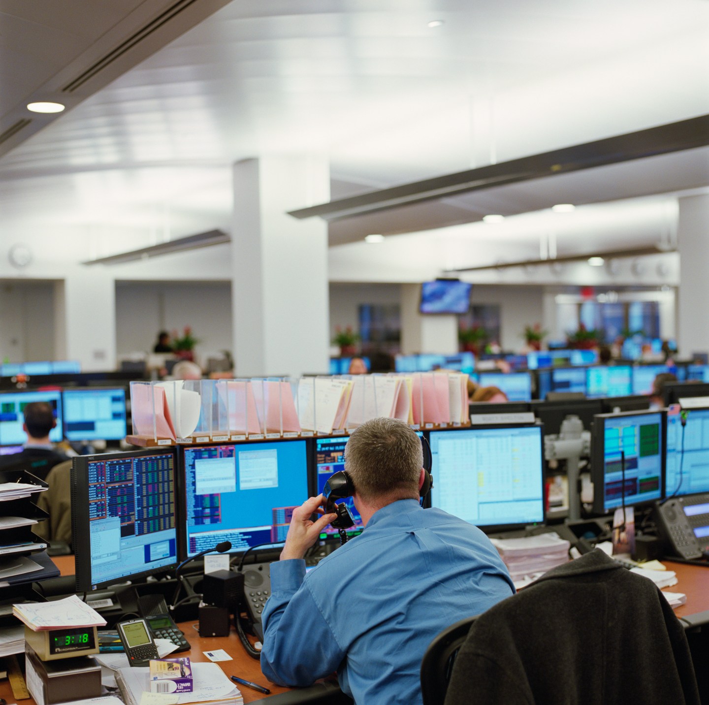 Male stock broker using telephone at desk, rear view