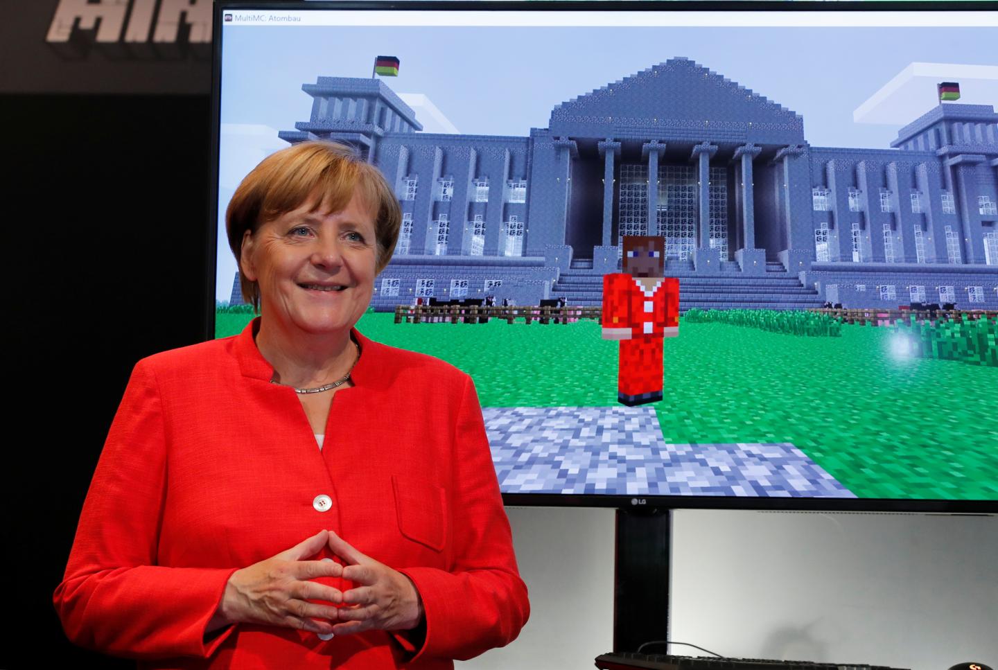 German Chancellor Angela Merkel stands next to a screen depicting a Minecraft rendition of her and the Reichstag building during the opening of the world's largest computer games fair Gamescom in Cologne