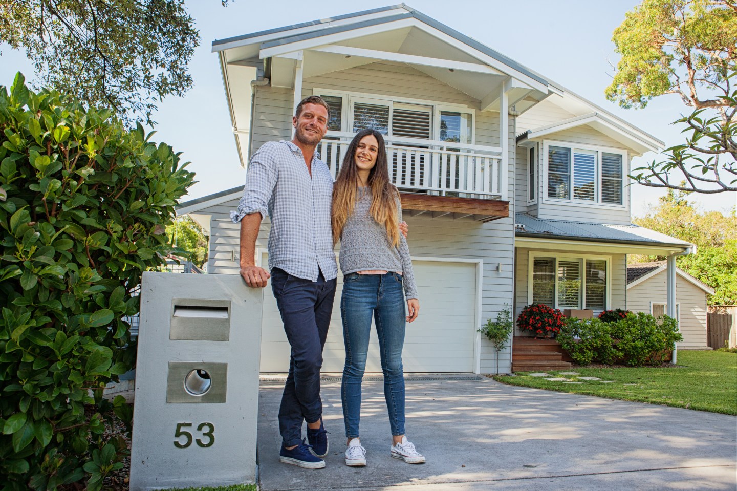couple standing by their mailbox in front of new home
