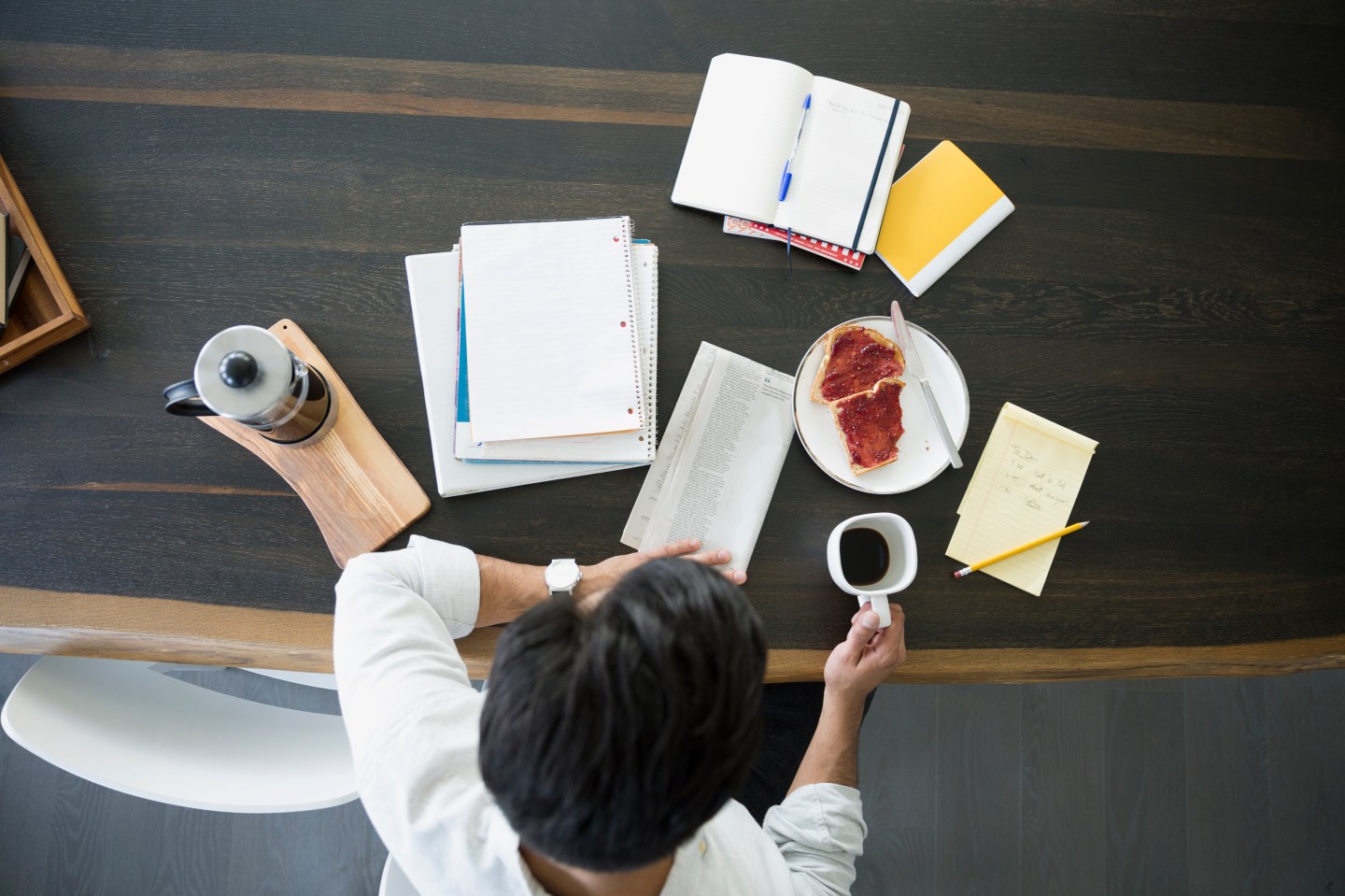 Overhead view of man with coffee newspaper table