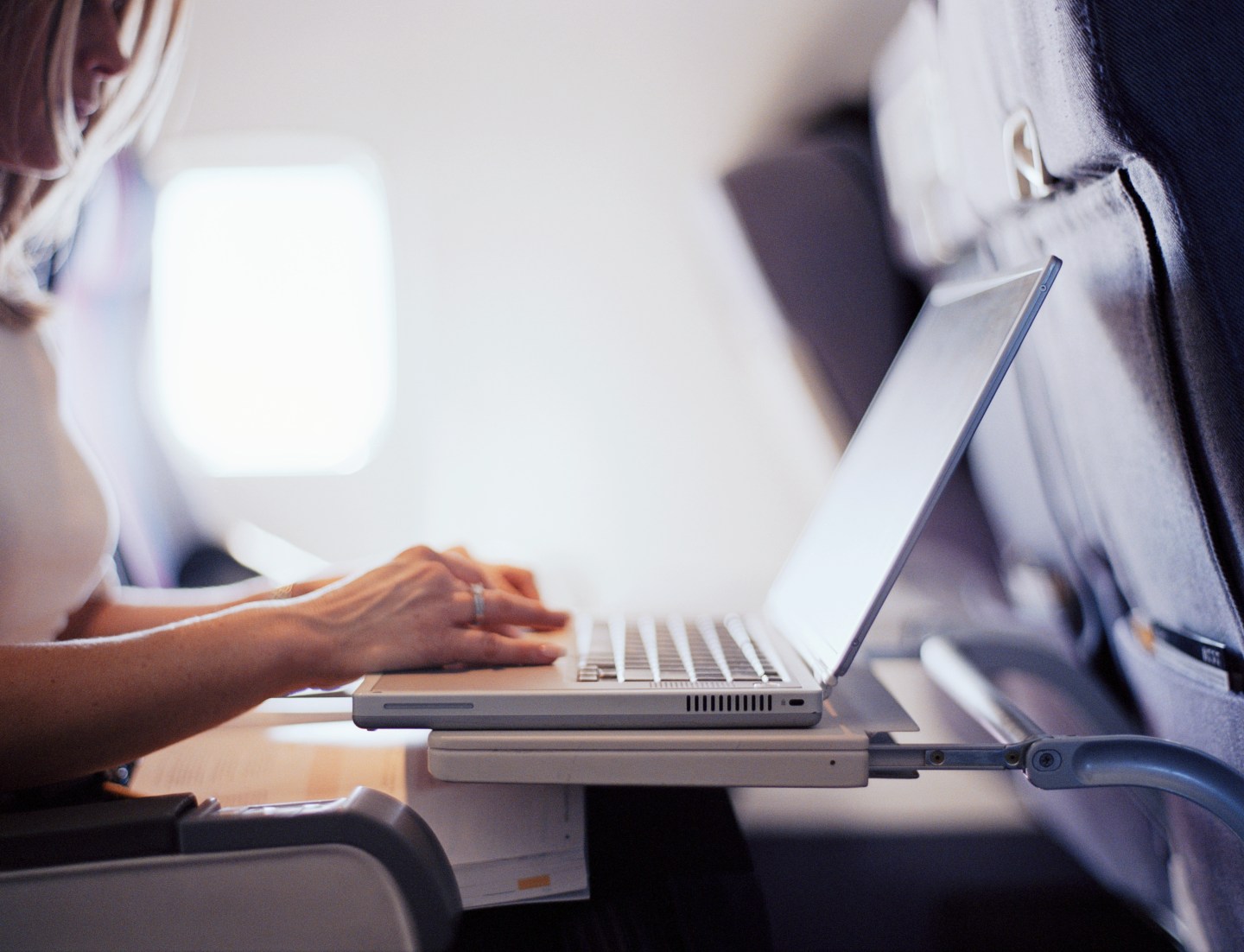 Woman typing on laptop computer in commercial airplane