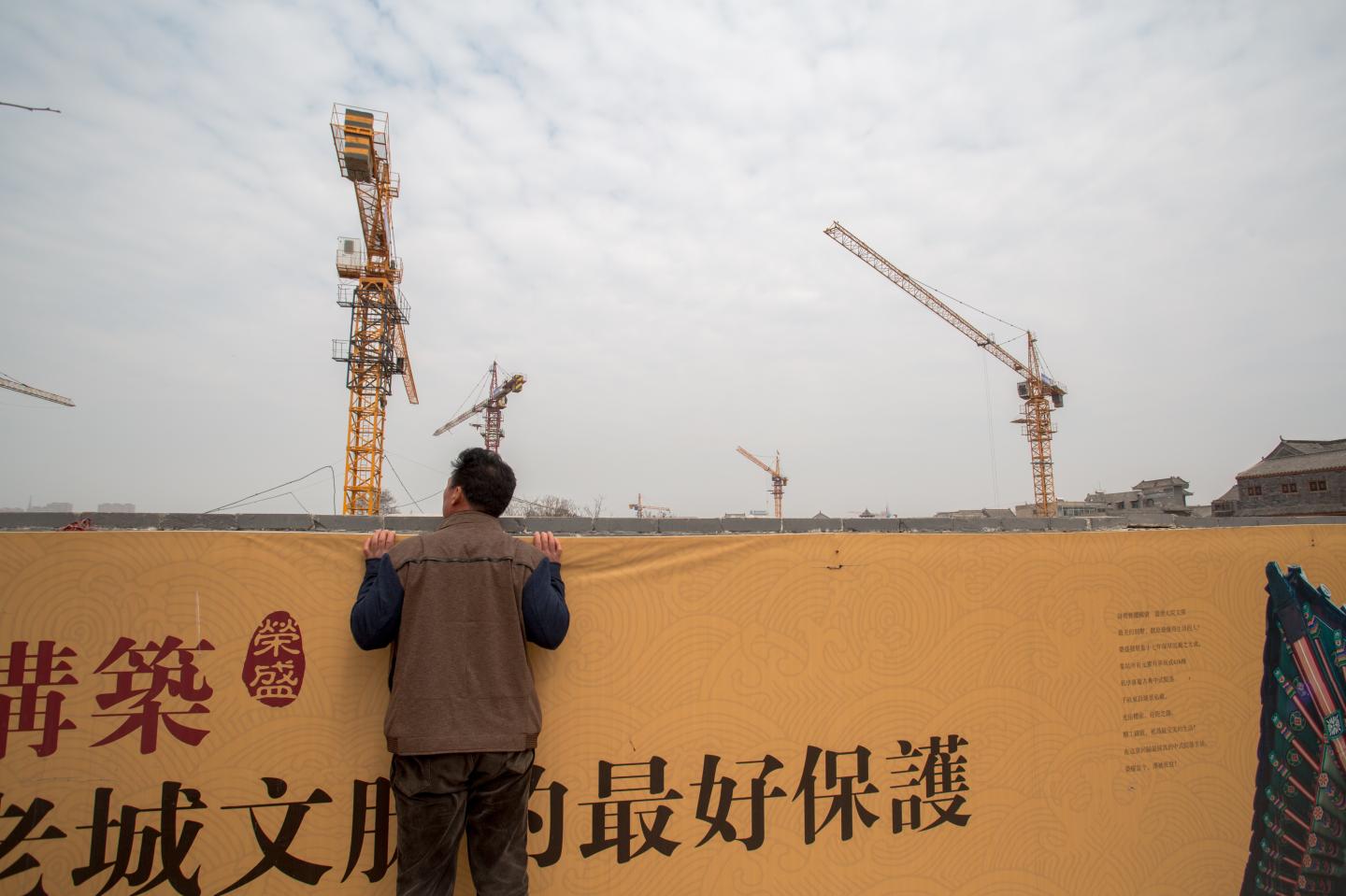 Pedestrian looks into a construction site of a high-end