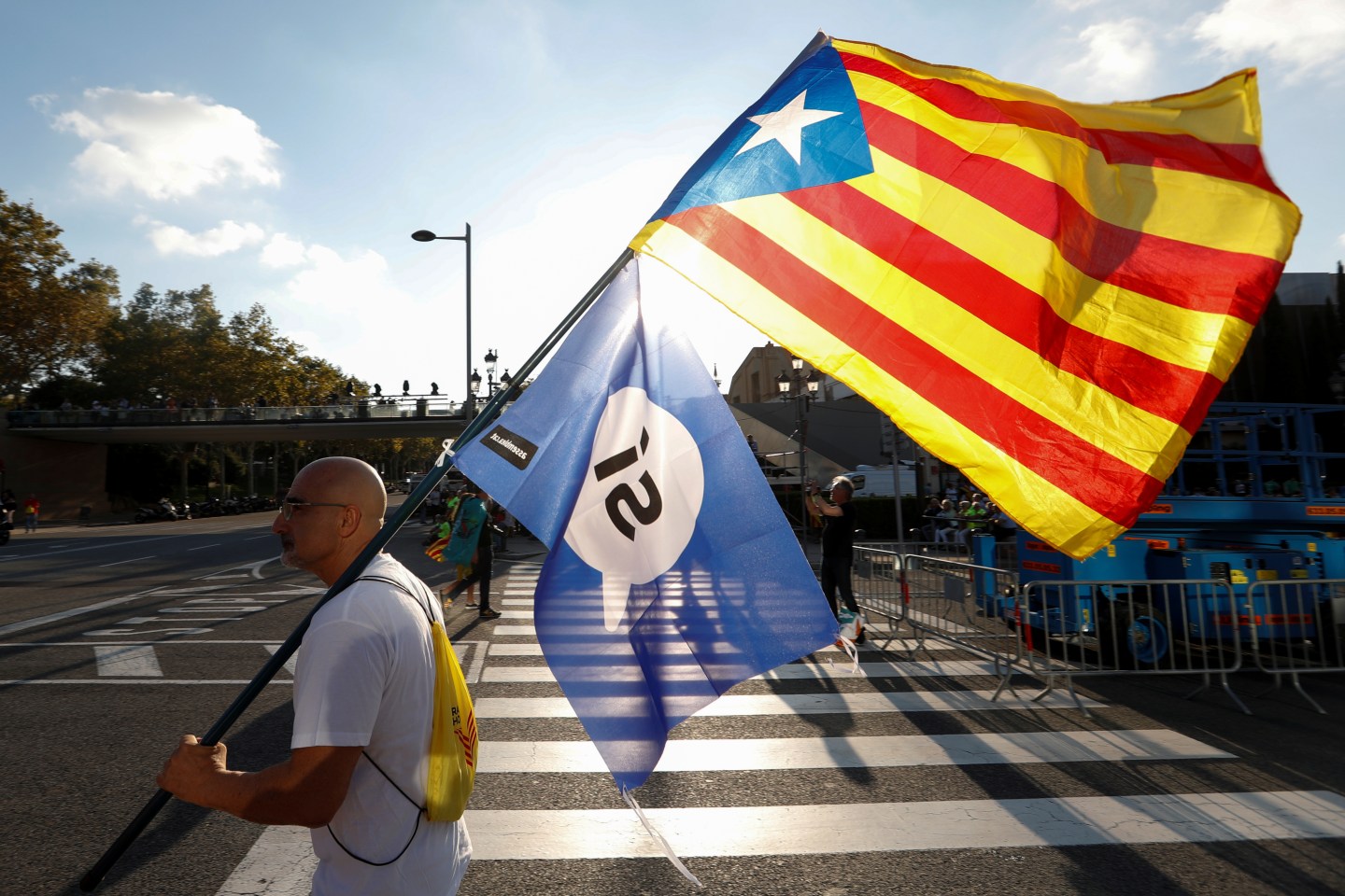A man holds an Estelada (Separatist Catalan flag) and a pro-referendum flag as he arrives at a closing rally in favour of the banned October 1 independence referendum in Barcelona