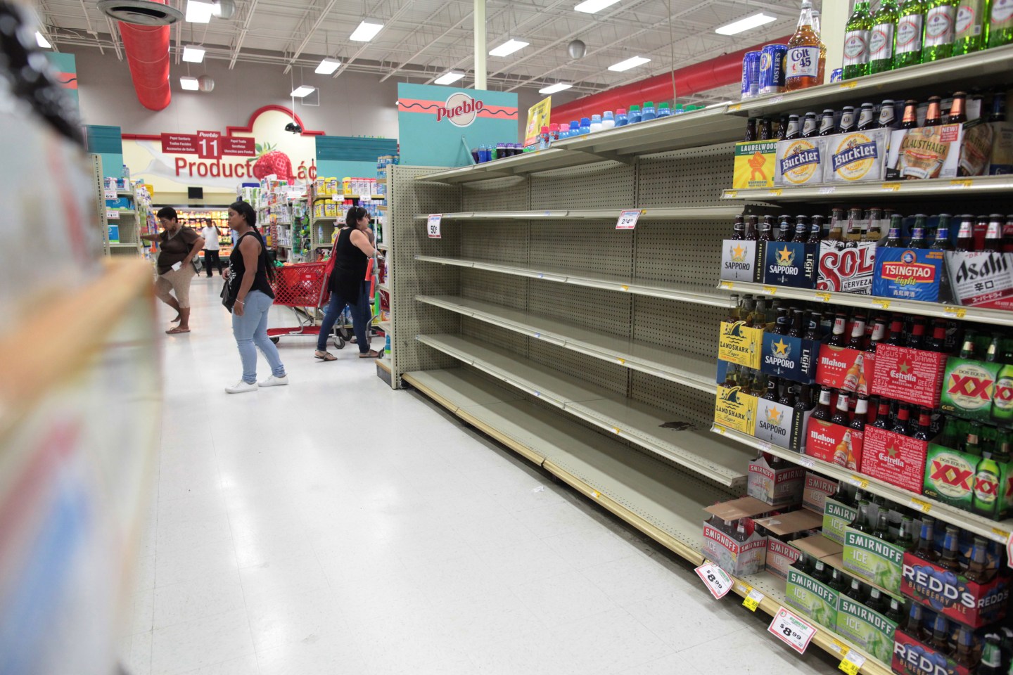 Customers walk near empty shelves that are normally filled with bottles of water after Puerto Rico Governor Ricardo Rossello declared a state of emergency in preparation for Hurricane Irma, in San Juan