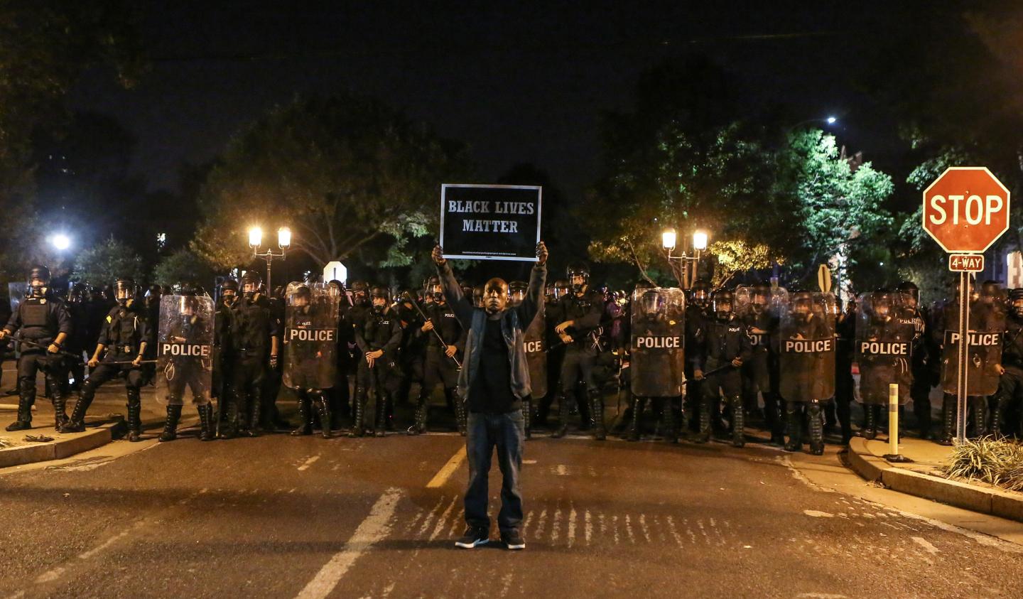 A Black Lives Matter protester stands in front of St. Louis Police Department officers equipped with riot gear in St. Louis