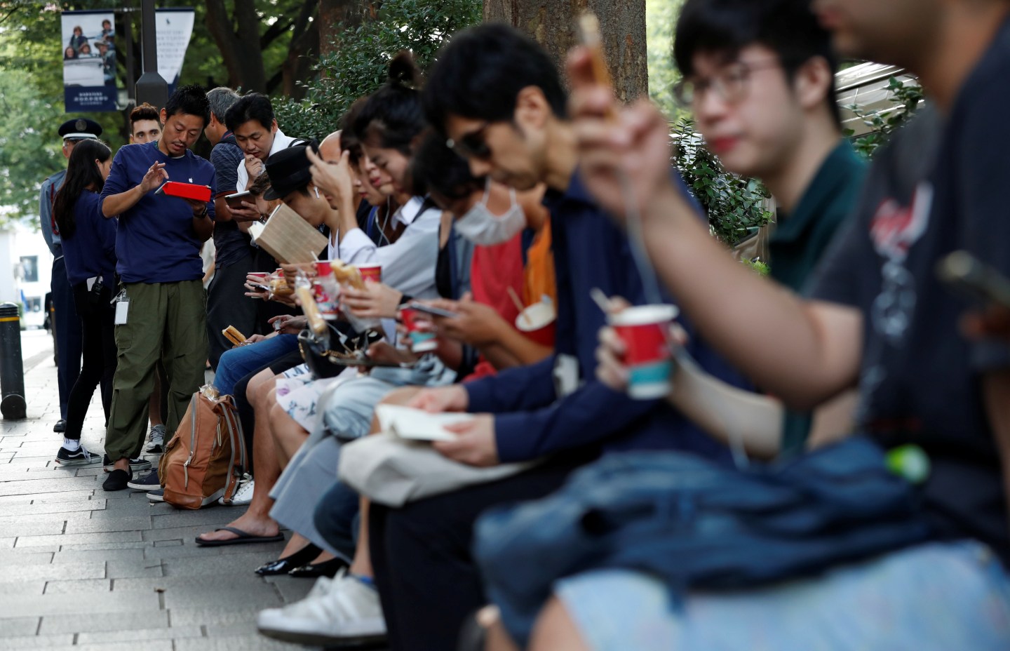 Customers sit in queue for the release of Apple's new iPhone 8 and 8 Plus outside the Apple Store in Tokyo's Omotesando shopping district