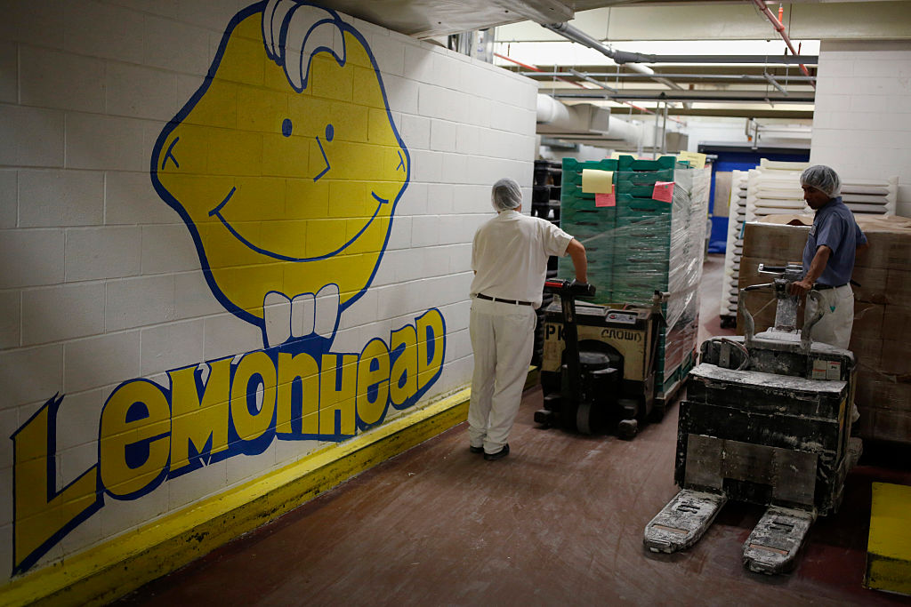 Factory workers move product near a Lemonhead candy mural inside the Ferrara Candy Company, Inc. factory in Forest Park, Illinois, U.S., on Tuesday, October 7, 2015. Photographer: Luke Sharrett/Bloomberg