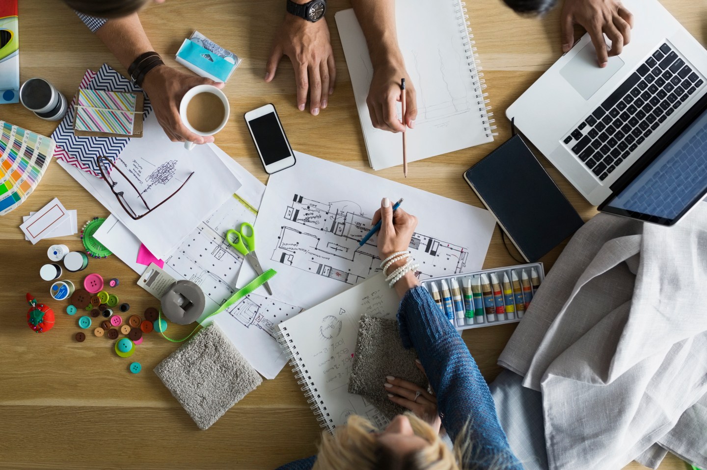 Overhead view of architects and designers reviewing blueprints