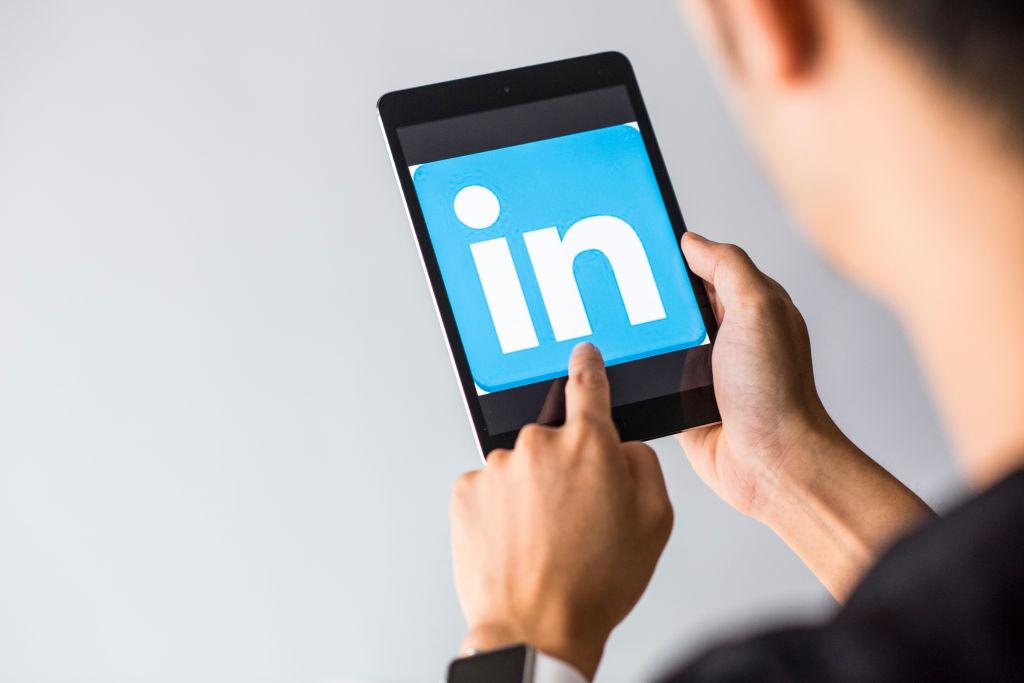 Young man holds a smart device while using Linkedin app