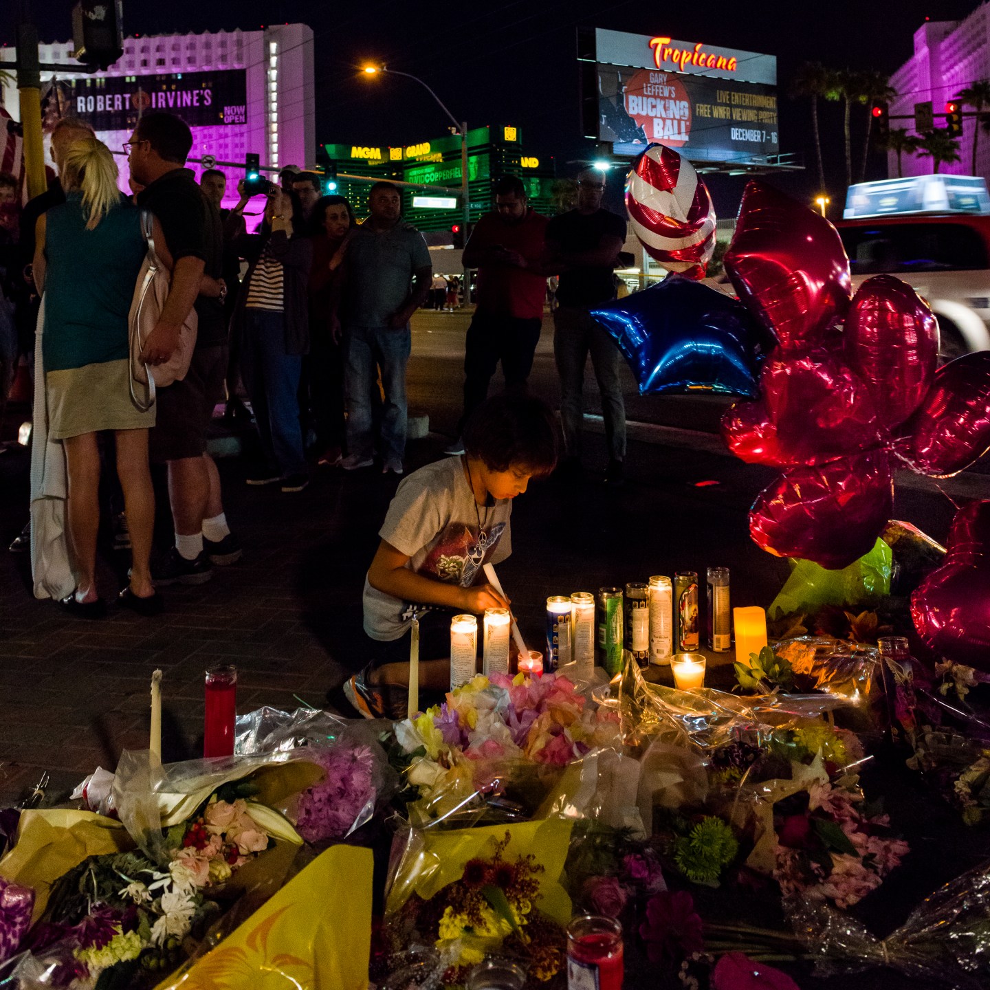 Child lights candles at a victims memorial vigil on Las Vegas Blvd. across from the Route 91 Festival location