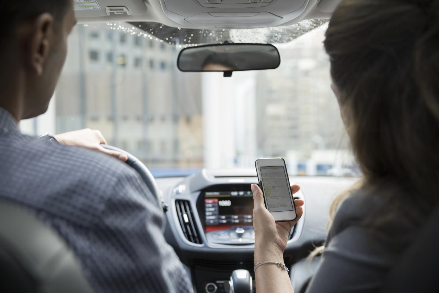 Businesswoman carpooling using cell phone in car