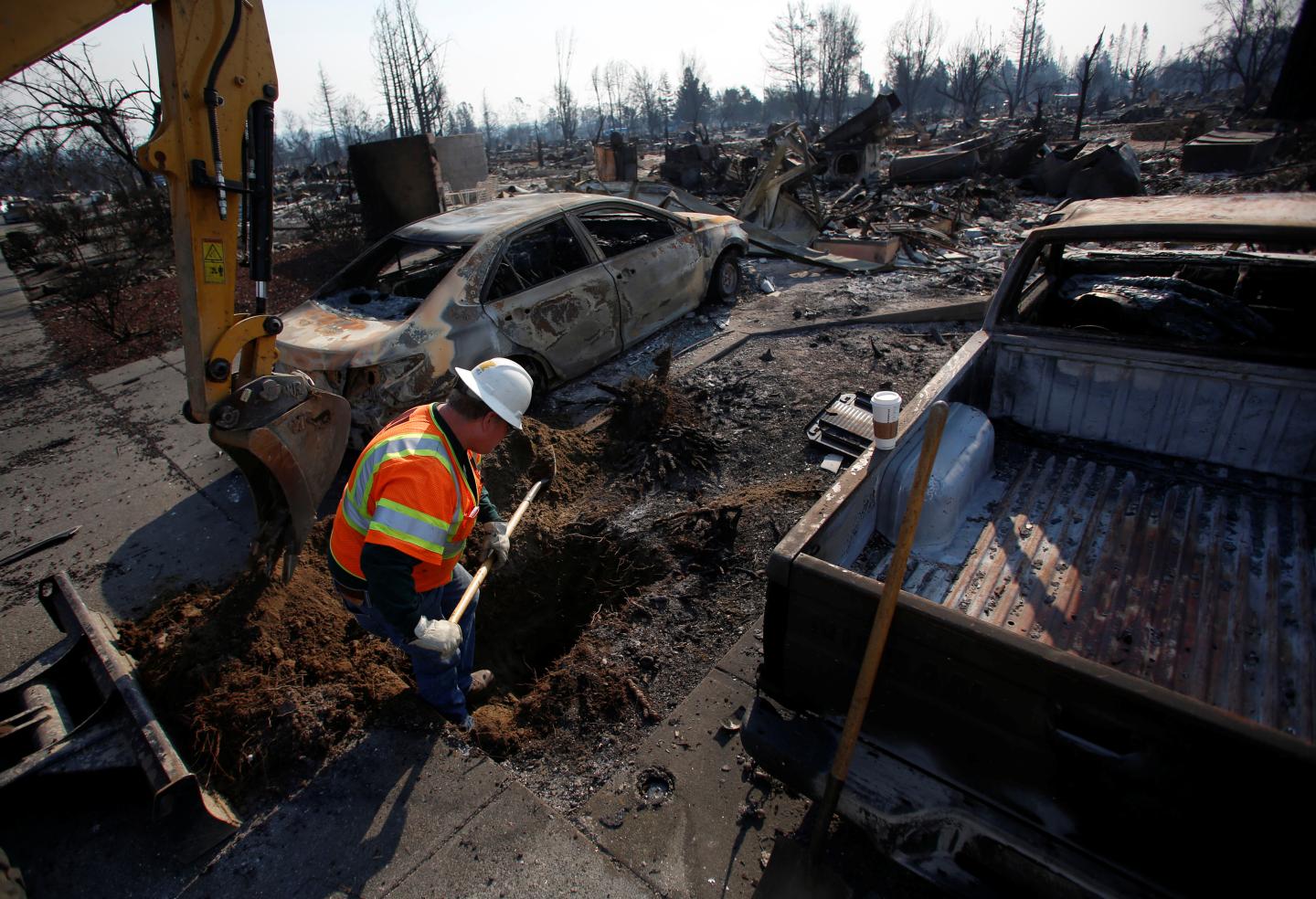 An employee of Pacific Gas &amp; Electric (PG&amp;E) digs to find an electrical transformer in a destroyed neighborhood after a wildfire tore through Santa Rosa, California