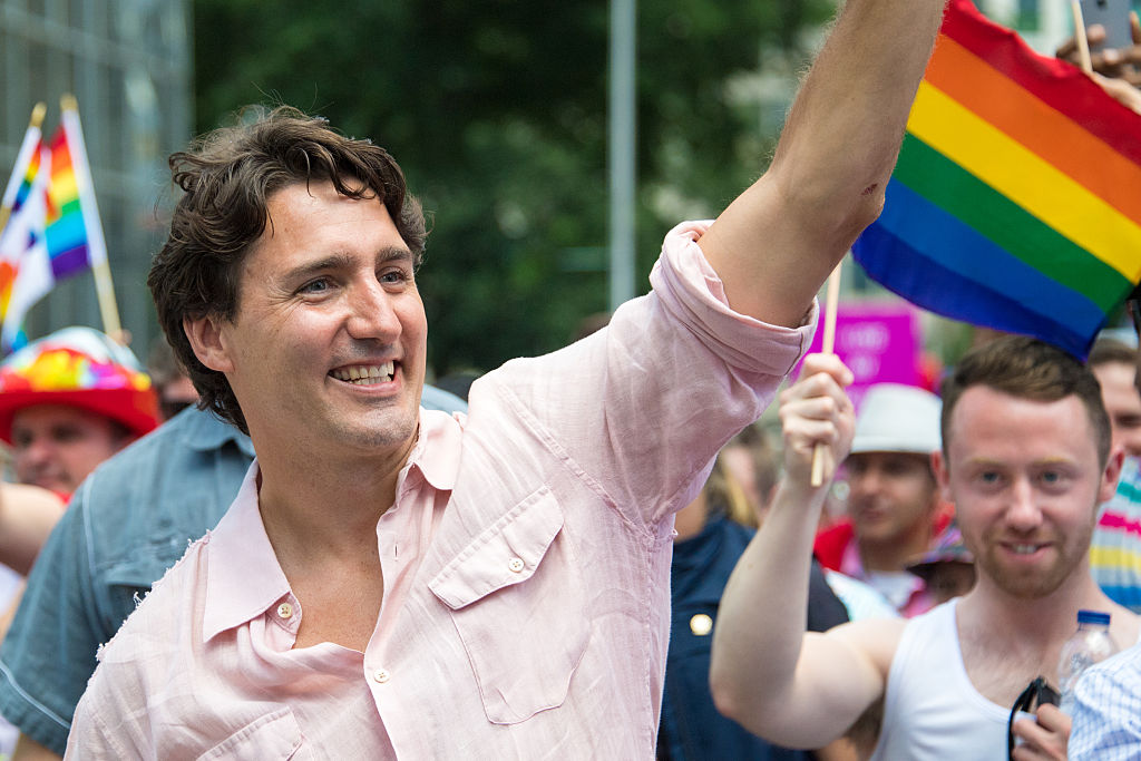 Justin Trudeau smiles and waves alongside LGBT flag at Pride parade