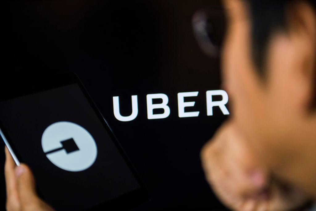 Young man holds a smart device while using Uber app