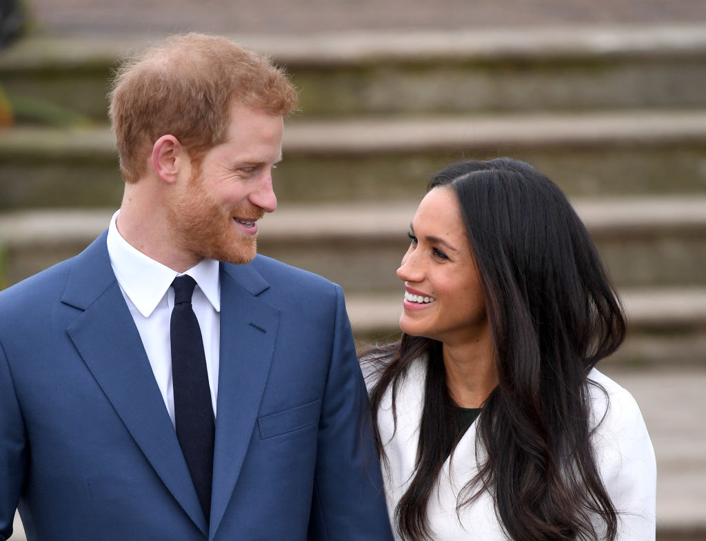 Prince Harry and Meghan Markle stand side by side, looking at one another, at official engagement photocall