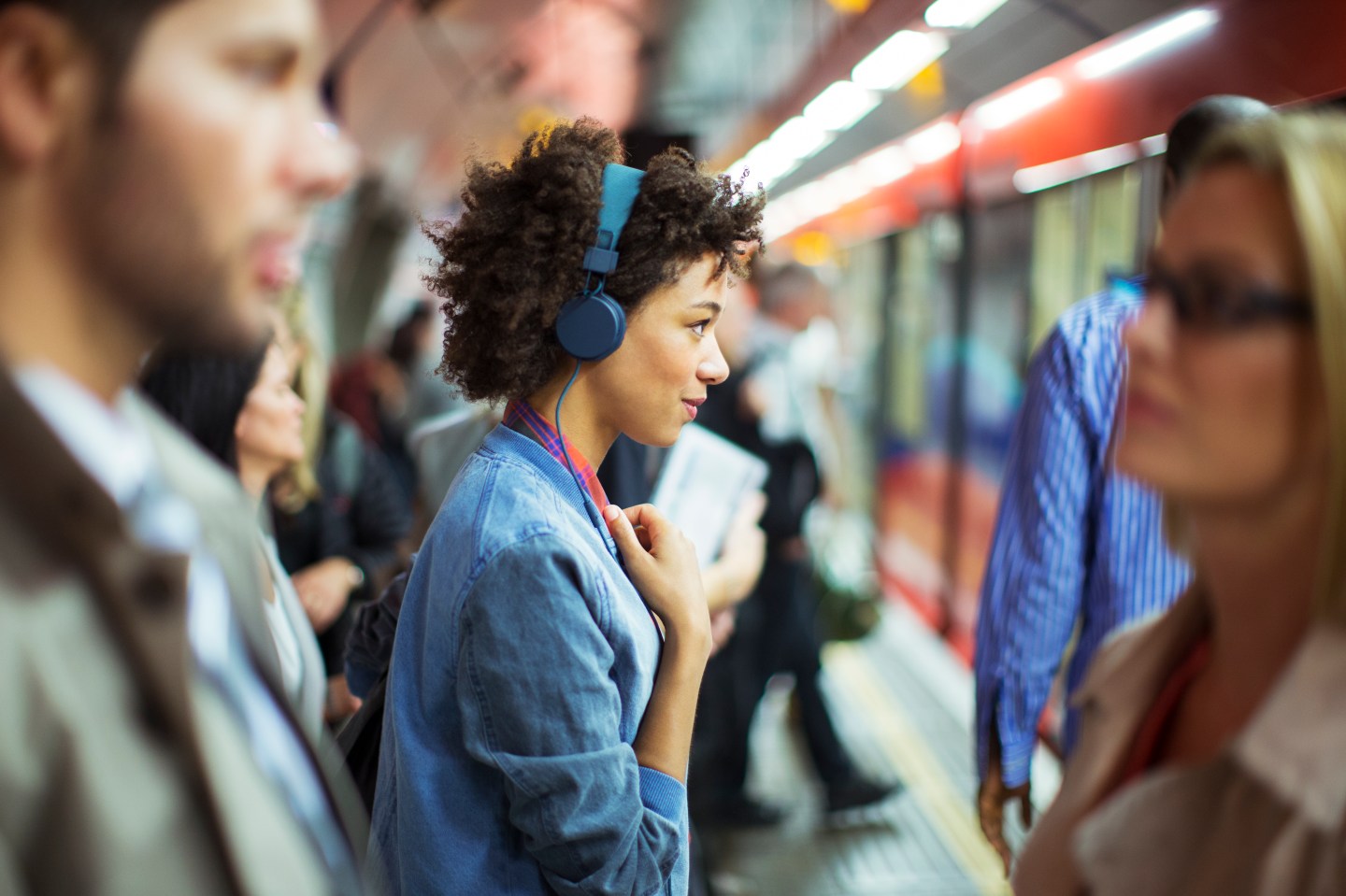 Woman listening to headphones in train station