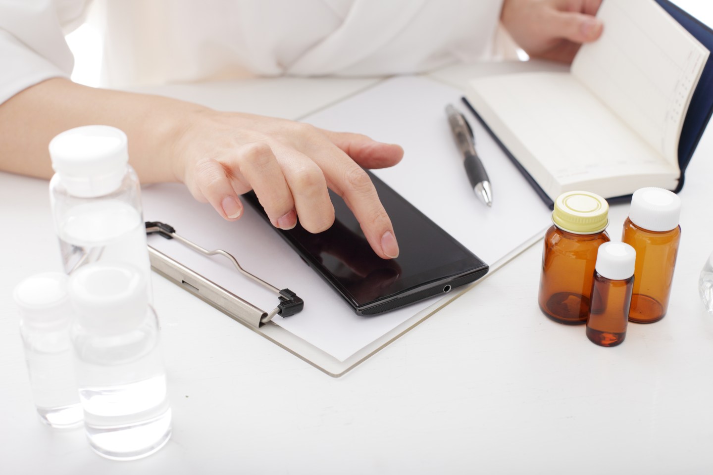 Female doctor sitting at desk using smart phone