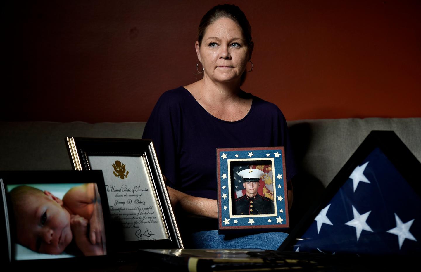 A woman holds a portrait of her deceased son, who was a retired Marine and addicted to opioids