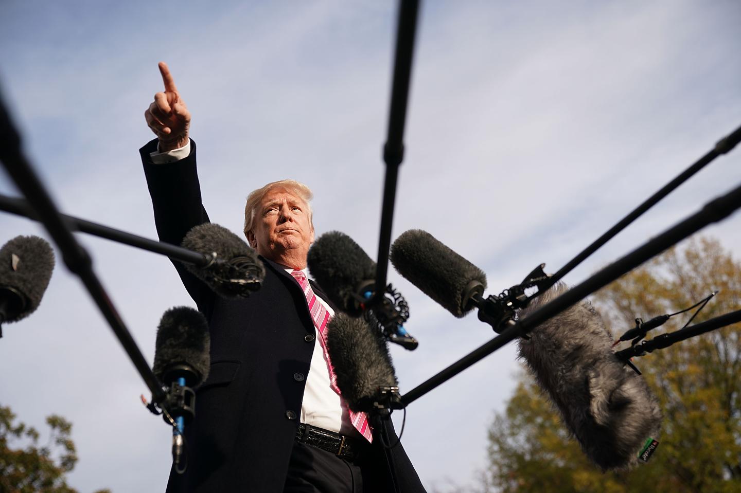 President Donald Trump points above a few microphones at a White House press conference