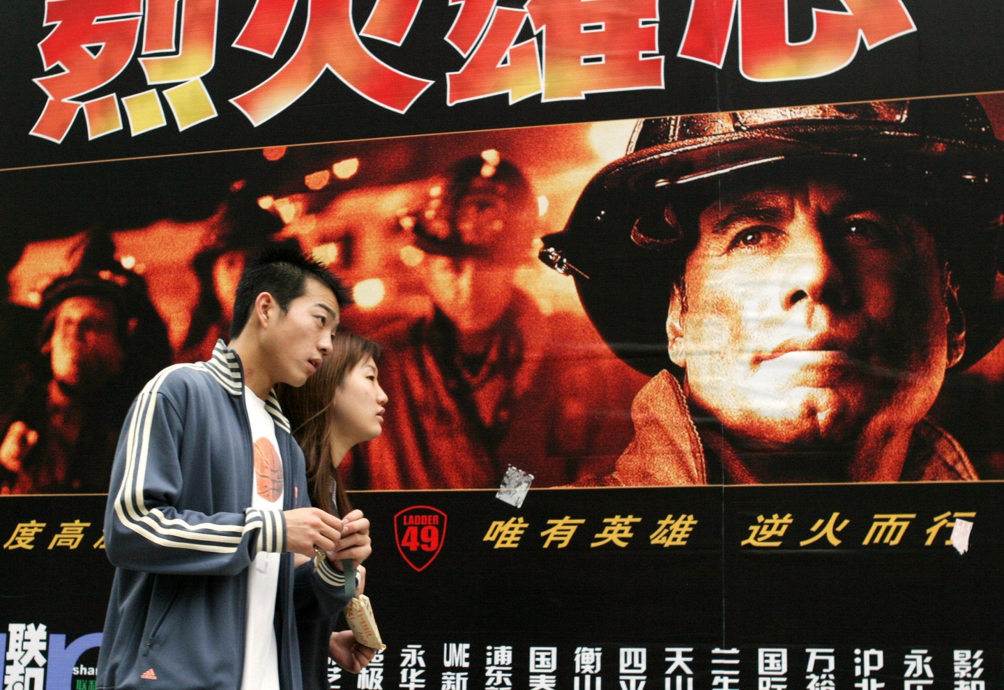 A couple walk past a billboard featuring a U.S. movie on the