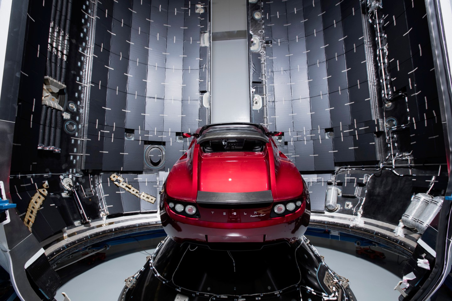A 2018 Tesla Roadster positioned inside SpaceX's Falcon Heavy rocket as payload for eventual orbit around Mars.