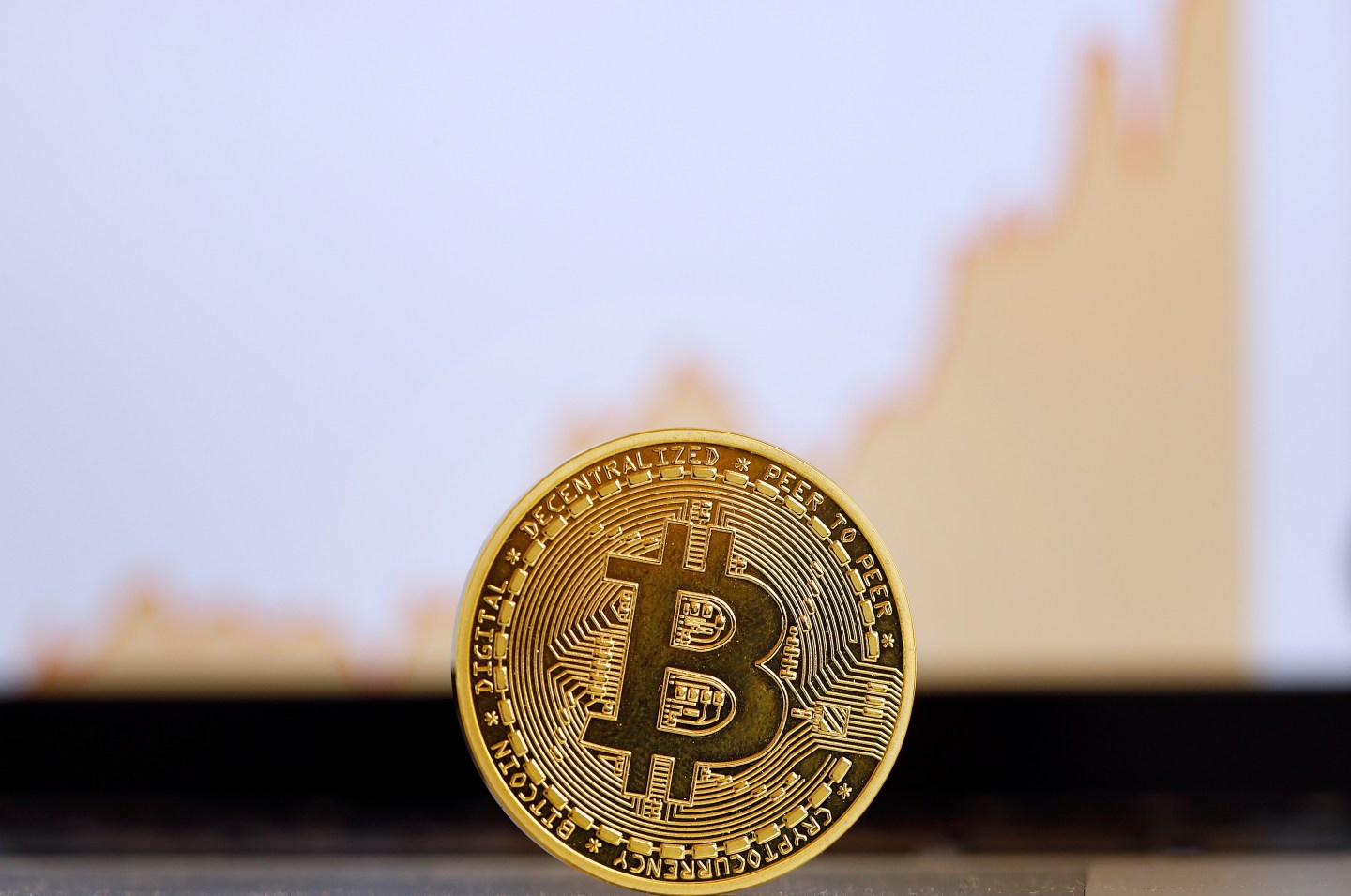 The digital cryptocurrency Bitcoin is visually displayed as a physical coin in front of a price chart is displayed on November 30, 2017 in Paris, France.