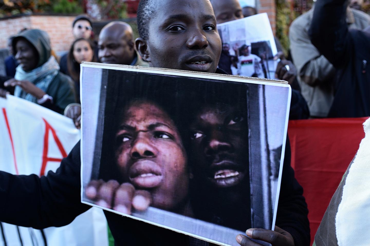 A man holds a photo during a protest against against slavery in Libya in front of the Libya embassy in Madrid on 26th November, 2017.