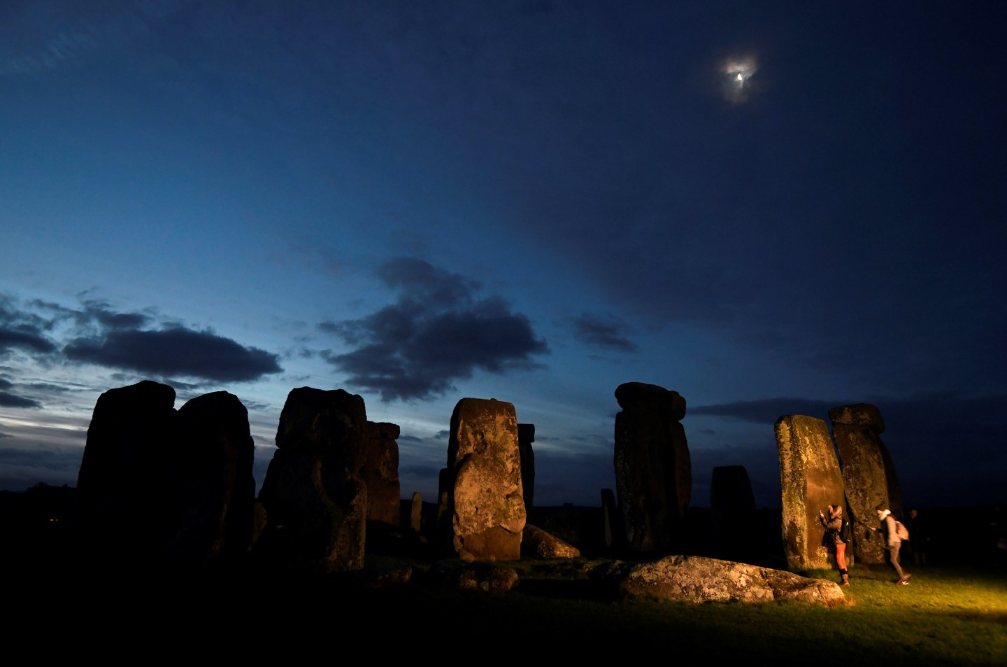 Visitors take photos amongst the prehistoric stones of the Stonehenge monument at dawn on Winter Solstice, near Amesbury