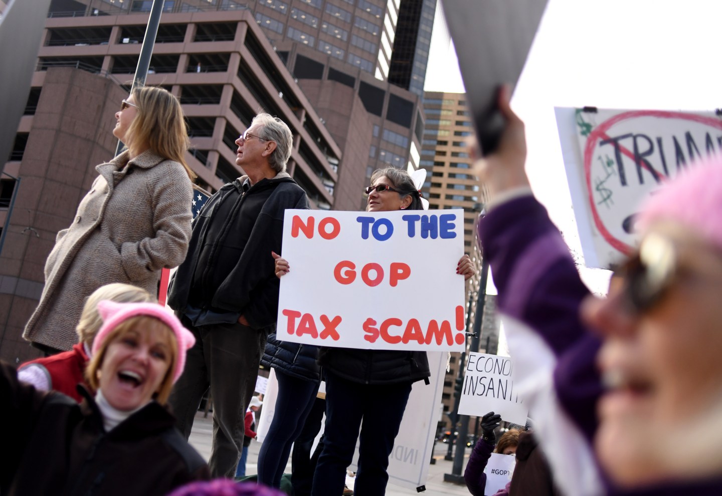 Demonstrators gather to protest the GOP tax reform bill. One sign reads "No to the GOP tax scam!"