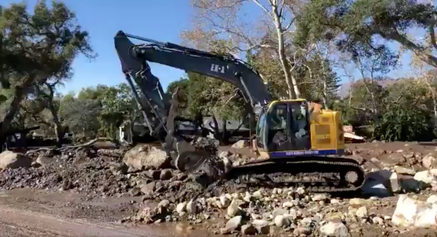 A Santa Barbara County Fire excavator clears large boulders from roadways following the mudslide in Montecito