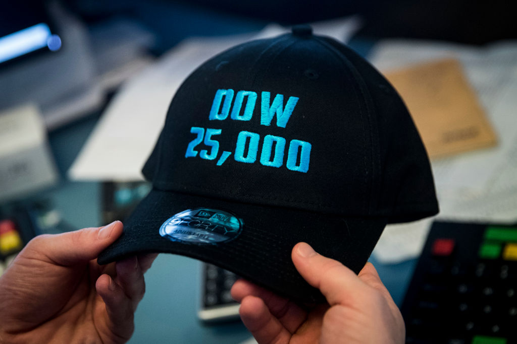 A trader holds a baseball hat that says 'Dow 25,000'