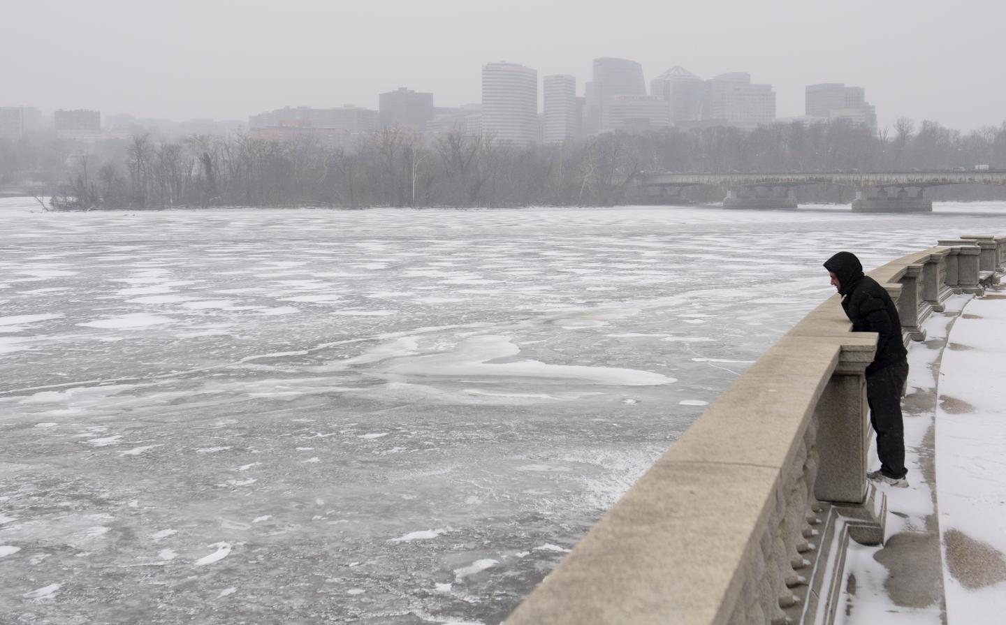 A man looks out over a frozen Potomac River during a snow storm in Washington, DC, January 4, 2018.