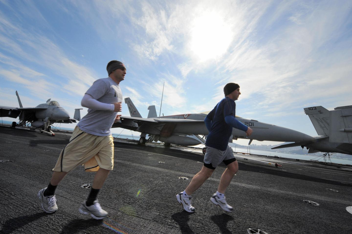 US Navy crew jog on the flight deck of t
