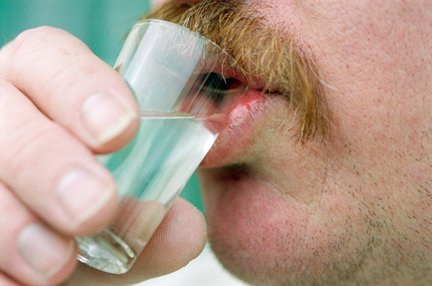 Man with mustache drinking from shot glass