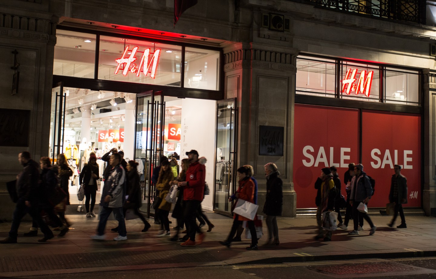 People walk past a 'sale' advertisement from an H&amp;M store on