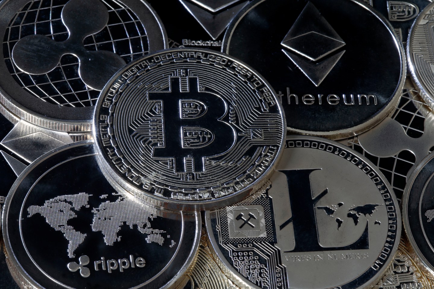 Digital cryptocurrencies Ripple, Bitcoin, Ethereum, and Litecoin represented as silver coins.